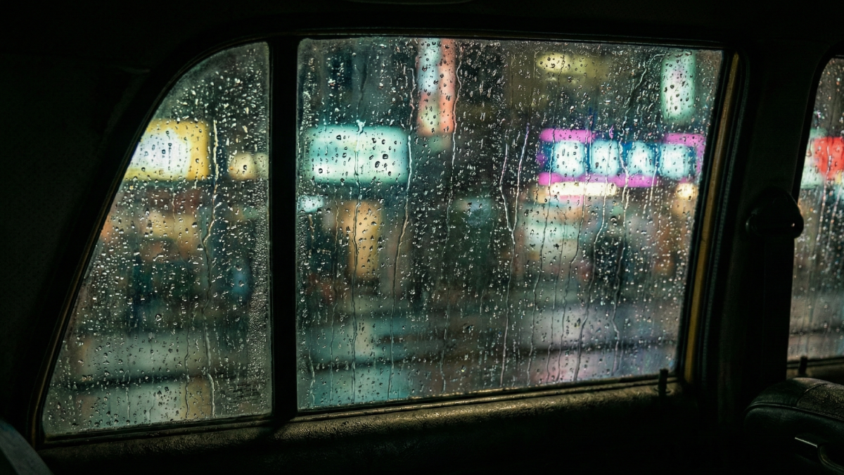 夜の雨に濡れるタクシーの窓越しに見える、遠ざかる人影のイメージ