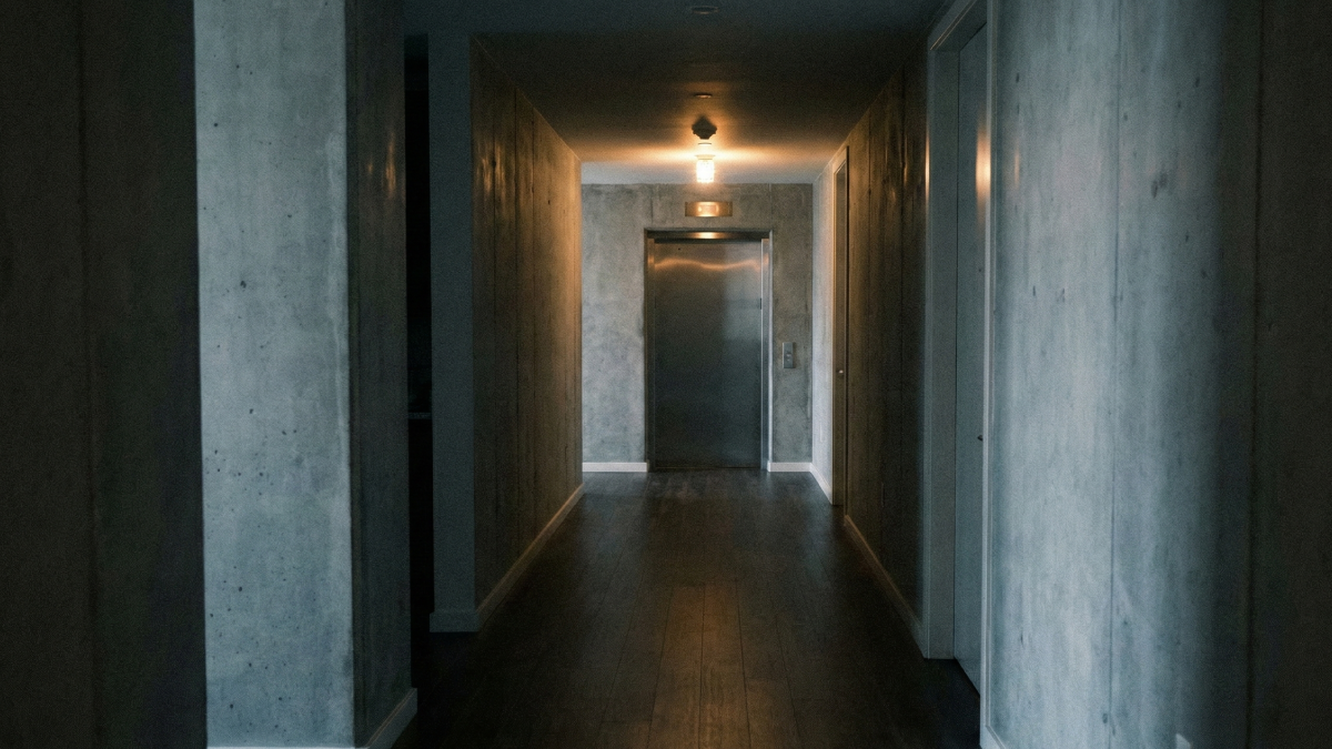 マンションの廊下とエレベーター前。静かな日常の中に不穏さが混じる空気を感じさせるイメージ